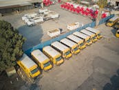 Aerial view of school buses and trucks parked in an industrial lot.